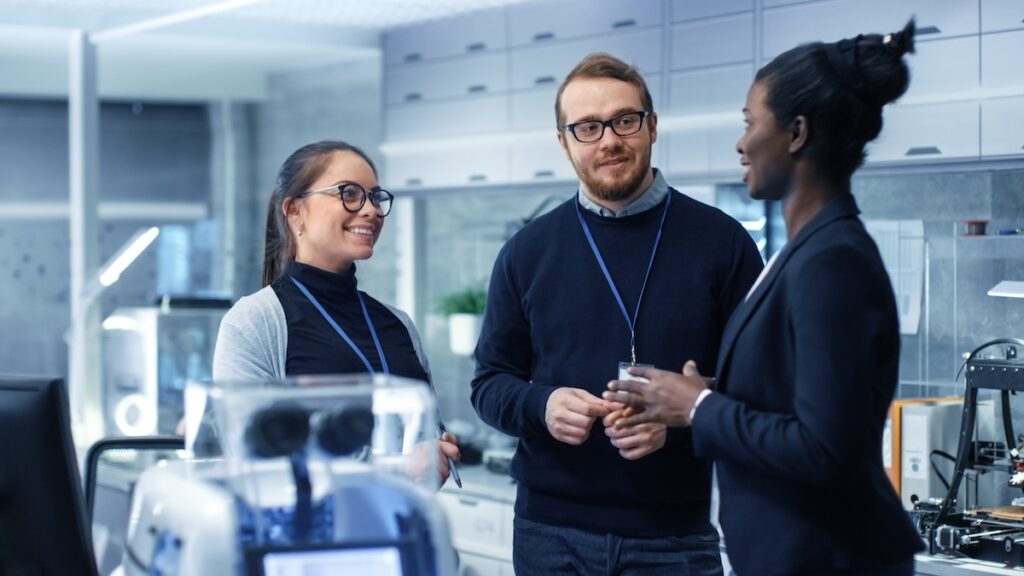 Multi Ethnic Team of Male and Female Leading Scientists Discussing Innovative Robotics Technology. They Work in a Modern Laboratory/ Research Center.